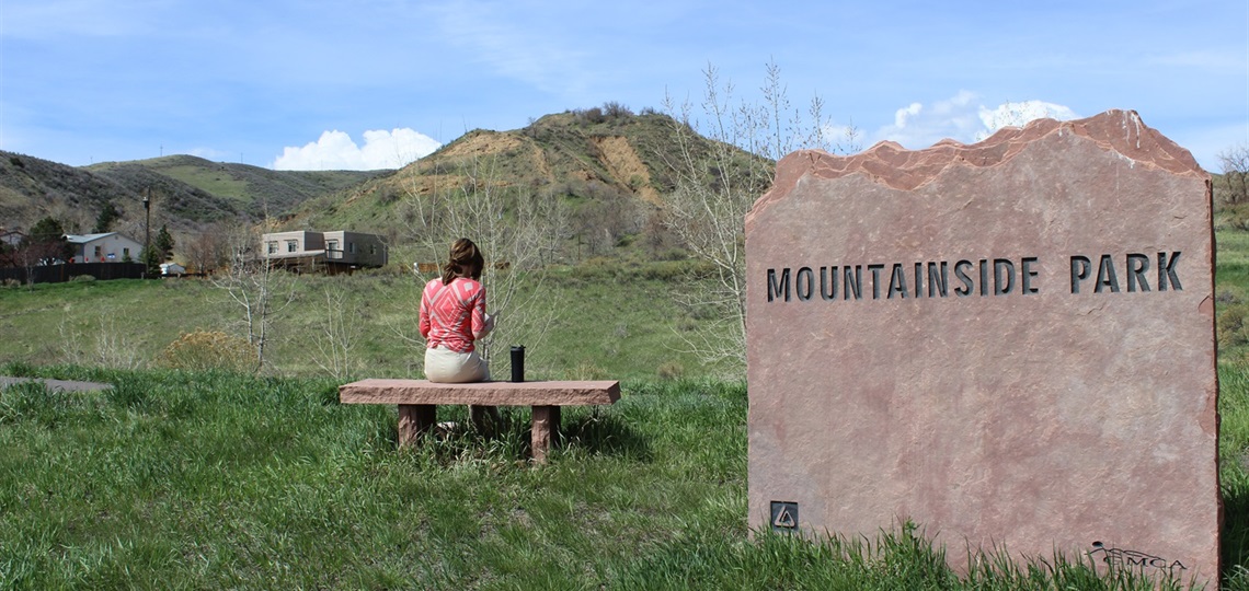 Mountainside Park with sign and woman on bench