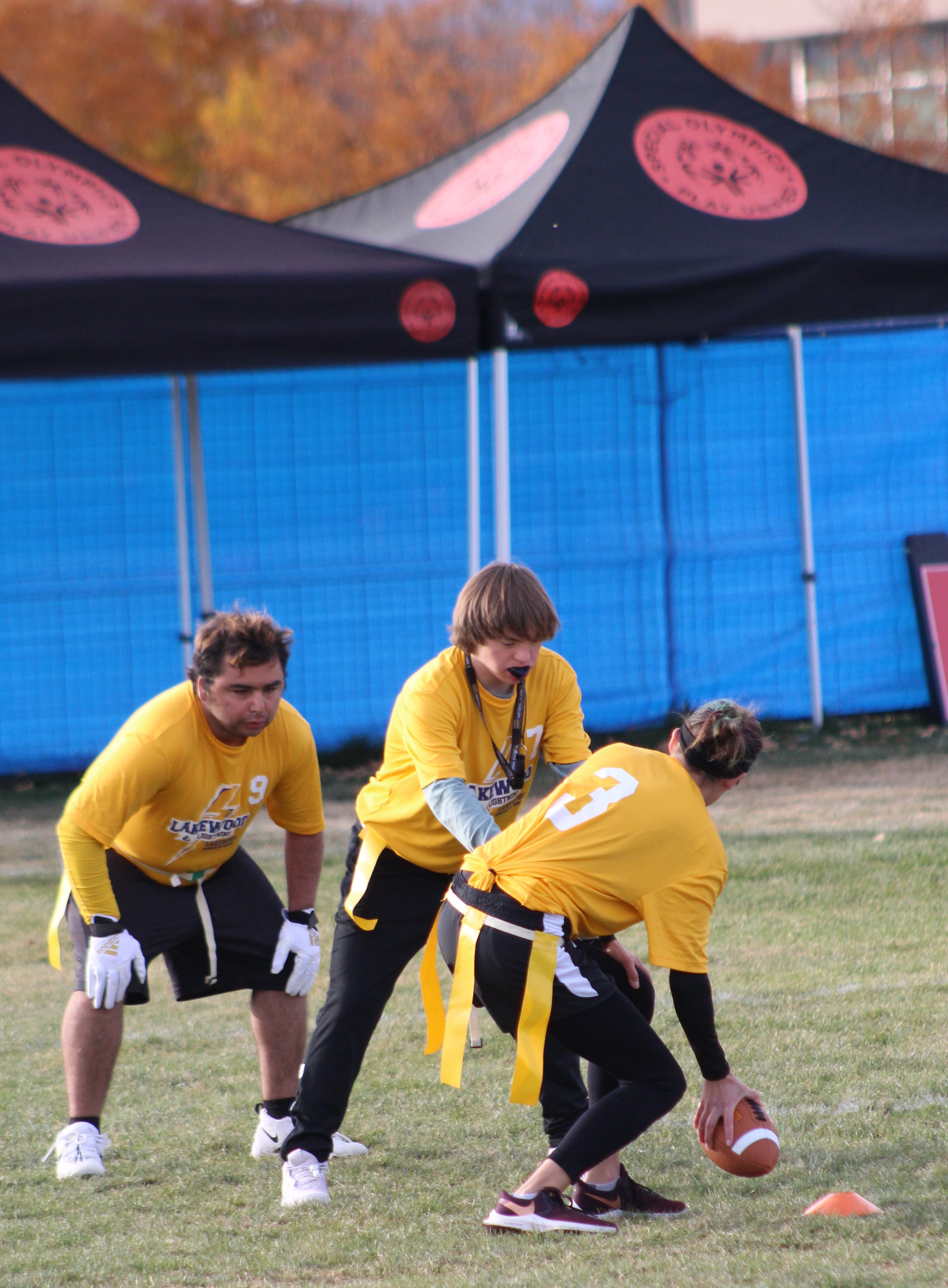 Yellow-shirted flag football players on the field at Special Olympics