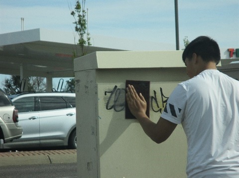 Person cleaning up graffiti.