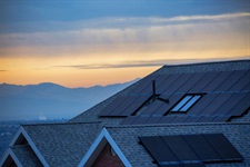 Roof of a house with mountains in the distance during sunset