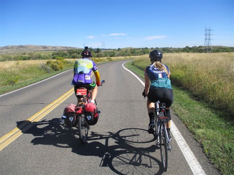 Two bicyclists riding down a road