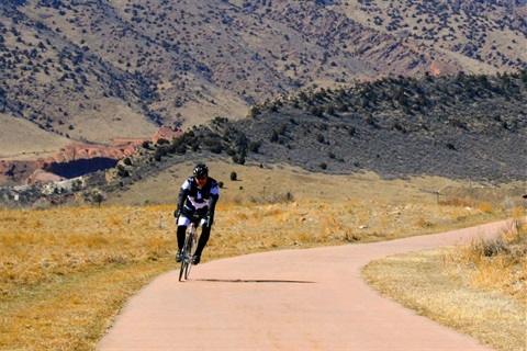 Man riding down a bike path with mountains in the distance